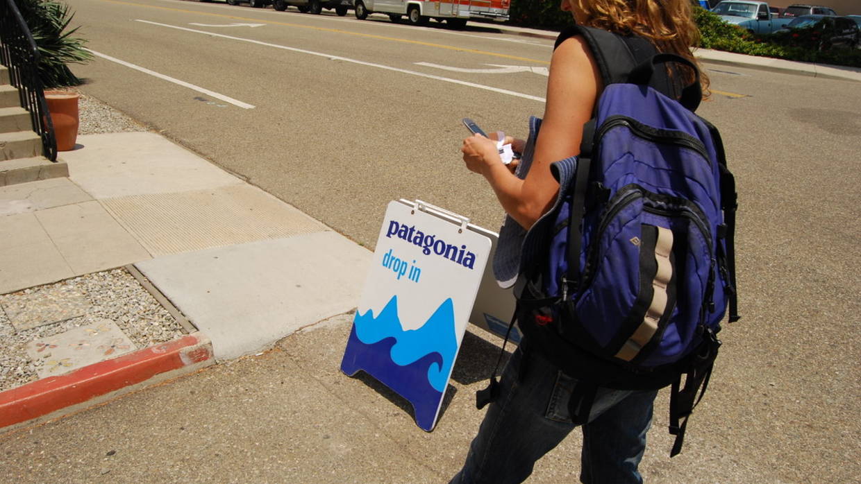 A woman walks past a "drop in" sign before entering Patagonia athletic wear store.